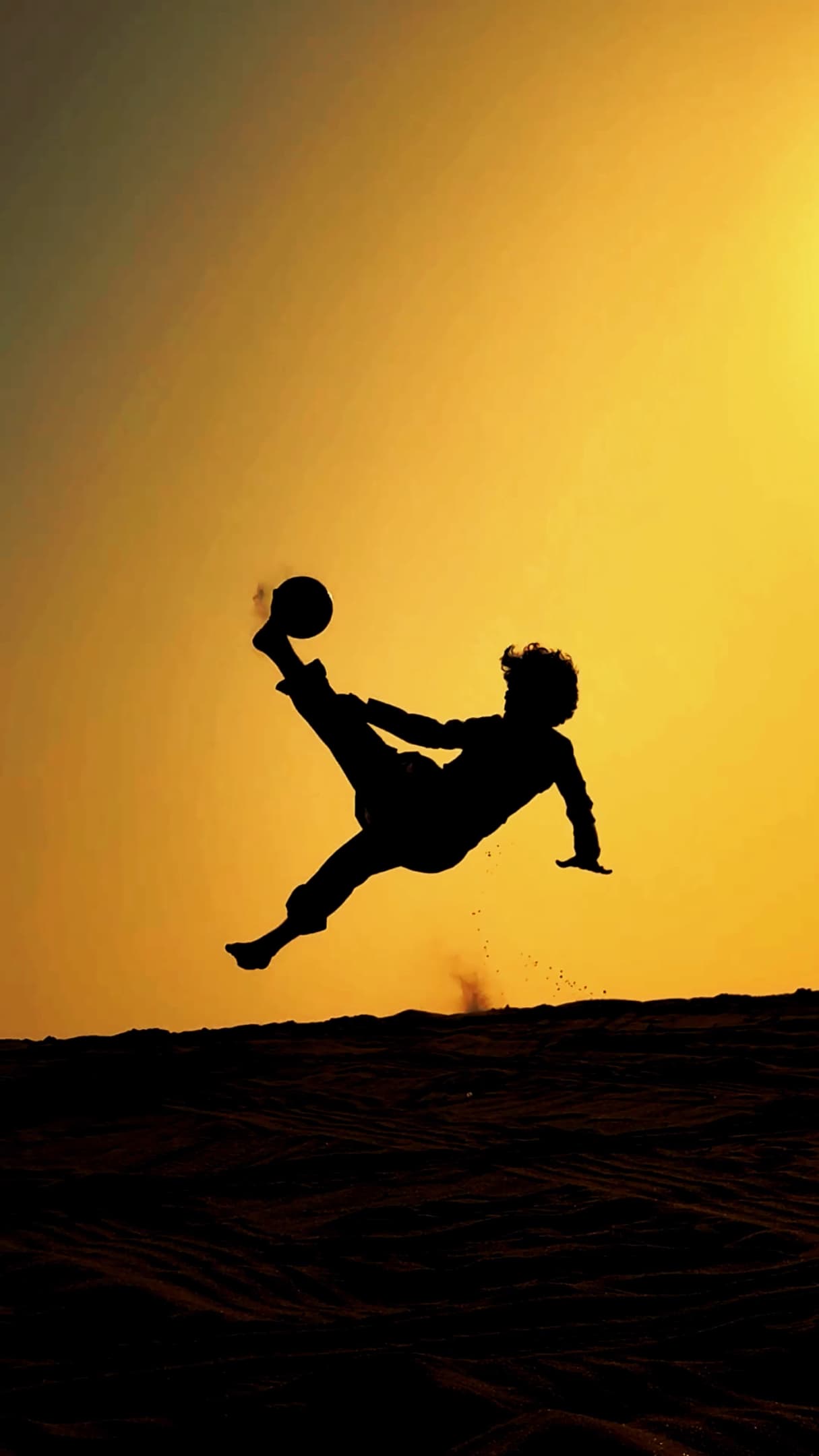 Sinan Basim silhouetted mid bicycle-kick in the desert at sunset